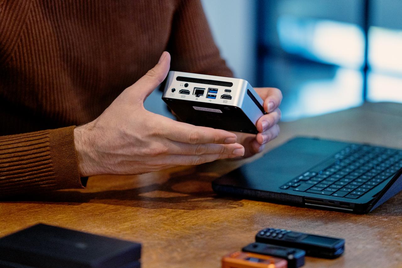 Hands holding Bitcoin hardware next to a laptop