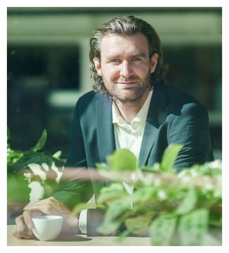Rob, bitcoinadviseur, in pak achter het raam met een kop koffie
